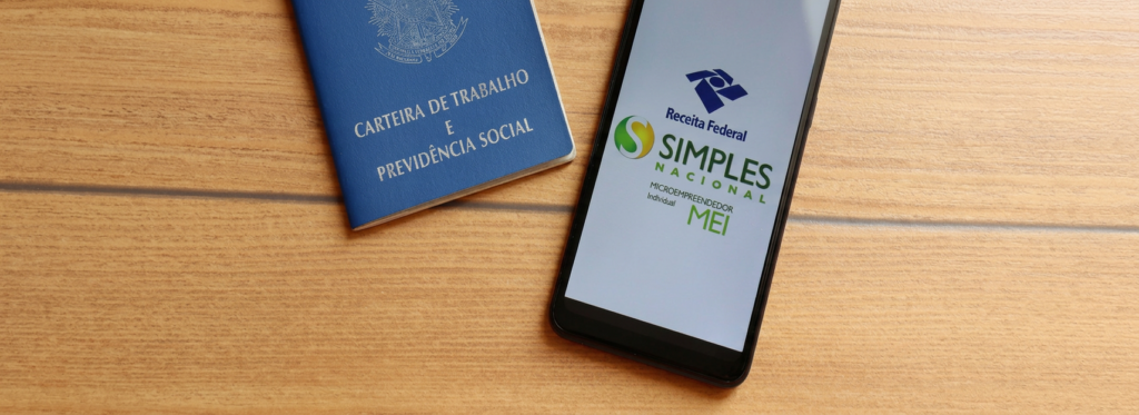 CLT e MEI: carteira de trabalho ao lado de celular com o aplicativo do MEI